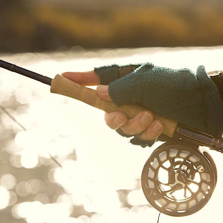 Green gloved hand holding fishing rod